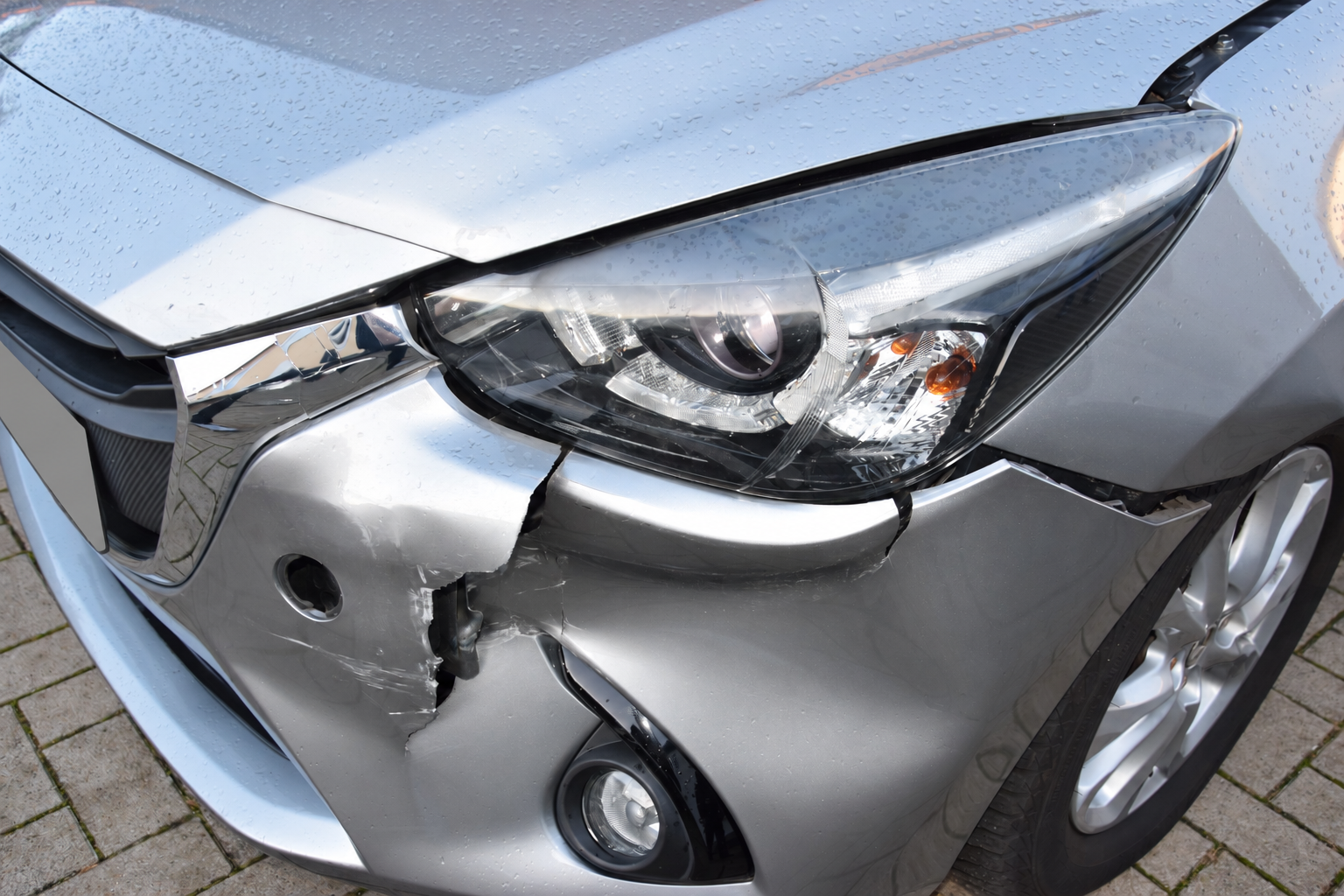 Frontschaden am silbernen Mazda 2 mit eingerissenem Stoßfänger; Kennzeichen verdeckt.